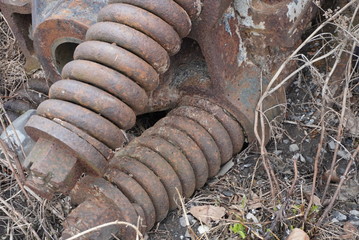 Old pieces of rusty equipment on the floor. Small rocks and dead vegetation.