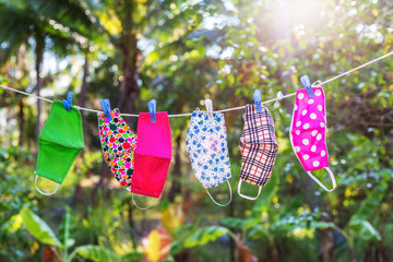 face masks with different style prints hang and dry on clothespins outdoors at sunset