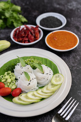 ืRice noodles in a banana leaf with beautifully laid vegetables and side dishes. Thai food.