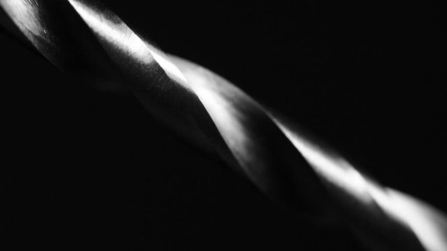 A light is move on a spiral of a steel drill bit on black background