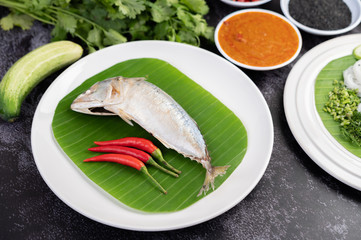 Mackerel placed on banana leaves on a white plate.