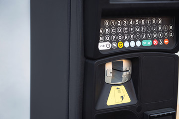 Modern automatic pay Parking meter or ticket payment station  on a street allow parkers, car drivers pay by card or cash cryptocurrency in the blurred background.