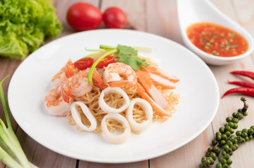 Stir-fried instant noodle with prawn and crab stick along  in a white dish.