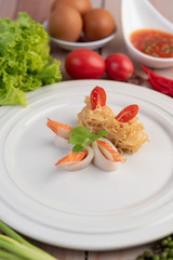 Stir-fried instant noodle with prawn and crab stick along  in a white dish.