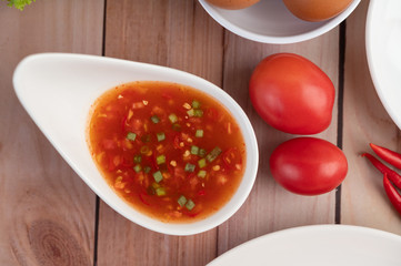 eggs, chili, tomato and sauce in a white plate on a wooden.