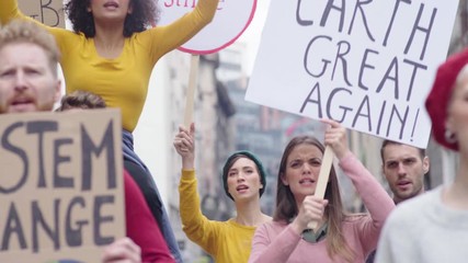 Group of multiethnic men and women protesting outdoors with placards. Group of demostrators with banners protest as part of a climate change. Protestors holding signs and posters on global strike.