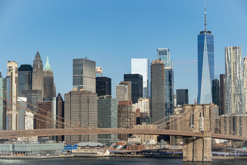 Manhattan skyline with Brooklyn bridge. Sky-rise skyscrapers tall apartment buildings. Dramatic cloudy sky with sun rays. 