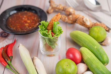 Shrimp deep fried batter placed on salad and tomatoes in a wooden bowl.