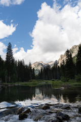 Grand mountains Grand Tetons in Wyoming. Mountain landscape with spring waters and mountain lakes. Blue sky. White clouds. Deep forest woods. 