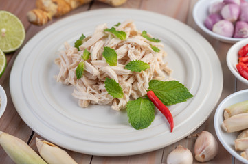The chicken that is bordered is cooked and placed in a white plate along with mint leaves.
