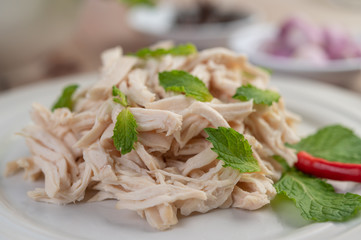 The chicken that is bordered is cooked and placed in a white plate along with mint leaves.