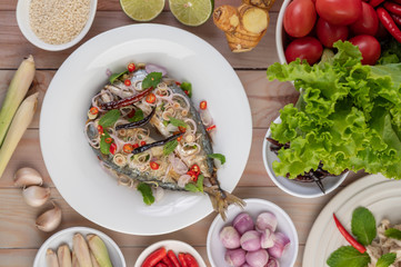 Deep-fried mackerel topped with galangal, pepper, mint, red onion in a white dish.