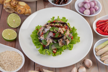 Deep-fried mackerel topped with galangal, pepper, mint, red onion in a white dish.