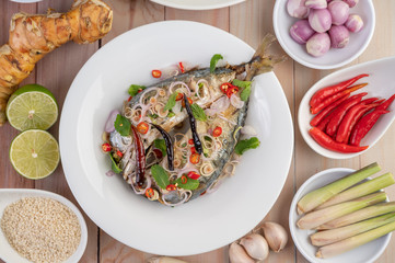 Deep-fried mackerel topped with galangal, pepper, mint, red onion in a white dish.
