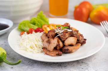 Grilled pork cutlet with tomatoes and salad, arranged in a white dish.