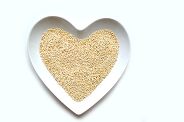 Organic gluten free quinoa grain in a heart shaped bowl on white with copy space 