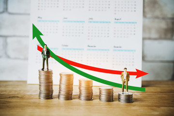 miniature business man and graph with row of  coins and calendar , business and finance concept