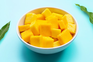 Mango cube slices in white bowl on blue background.