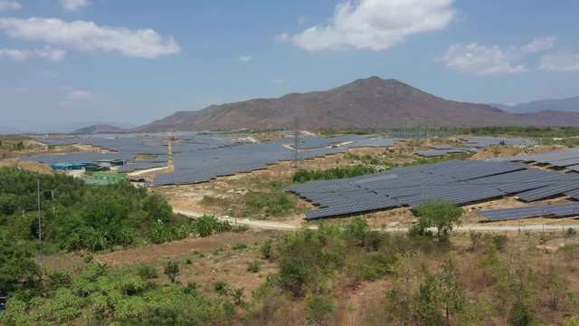 Solar panel produces green, environmentaly friendly energy from the setting sun. View from drone. Landscape picture of a solar plant that is located inside a valley, Ninh Son, Ninh Thuan, Vietnam