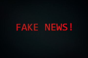 FAKE NEWS message on display screen black background technology alert computer or Mobile phone technology / reading fake news on internet concept