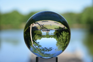 Obraz na płótnie Canvas Crystal lens refractory ball with an inverted image of landscape in the park 