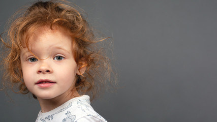 beautiful redhead little girl on gray background with copy space, cute baby mock up on banner