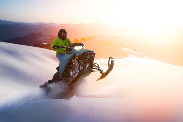 Adventurous Man Riding a Snowmobile in white snow during a colorful sunset or sunrise. Action Image...