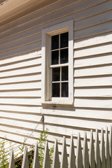 Window in exterior of a clapboard house wall, picket fence, generic architecture, vertical aspect