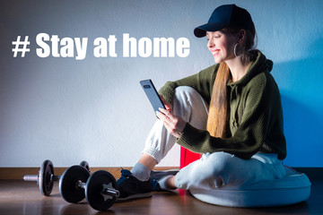 Sportswoman next to the #Stay at home sign. The girl encourages you to play sports at home. A call...