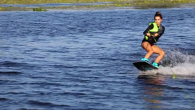Young sexy girl on bake board driving in swimsuit riding on waves 