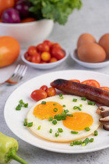 Breakfast consisting of bread, fried eggs, tomatoes, Chinese sausage and mushrooms.