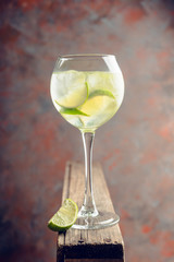 Rum based cocktail with lime in wine glass (variation of cuba libre) on the rustic background. Selective focus. Shallow depth of field.

