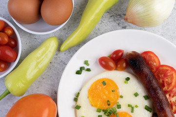 Breakfast consisting of bread, fried eggs, tomatoes, Chinese sausage and mushrooms.