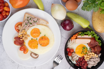 Breakfast consists of fried eggs, sausage, minced pork, bread, red beans and soy on a white plate.