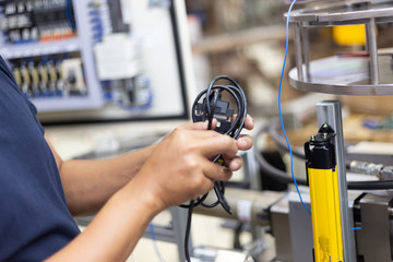 Technician setting  electric control box of machine in factory 
