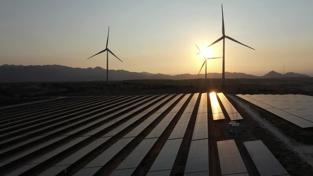Windmill and Solar panel produces green, environmentaly friendly energy from the setting sun. View from drone. Landscape picture of a solar plant that is located inside a valley, Ninh Thuan, Vietnam