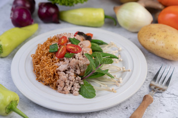 Stir-fried noodles with minced pork, edamame, tomatoes and mushrooms in a white plate.