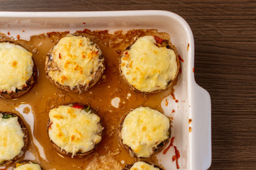 Baked stuffed mushrooms in a baking dish on a wooden table, top view