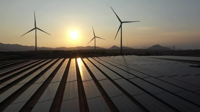 Windmill and Solar panel produces green, environmentaly friendly energy from the setting sun. View from drone. Landscape picture of a solar plant that is located inside a valley, Ninh Thuan, Vietnam