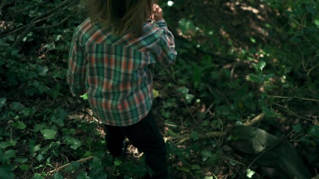 Little boy in the woods finding a walking stick