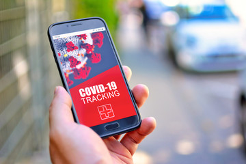 Corona Virus Tracking App concept with hand holding cell phone with application design on screen in...