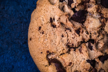 Detail of handmade chocolate chip cookie on dark blue background