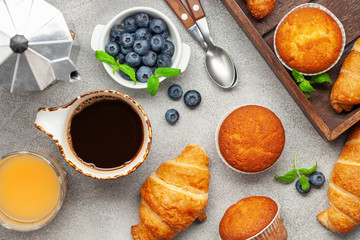 Continental breakfast captured from above (top view, flat lay). Coffee,  juice, croissants,muffins and blueberry.