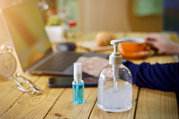 Coronavirus Business woman working from home wearing protective mask. Working from home . Cleaning her hands with sanitizer gel .