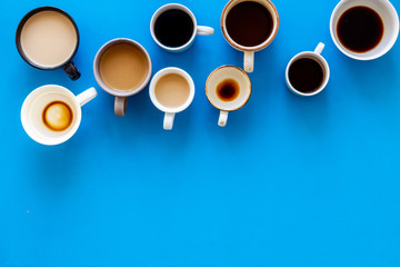 Cups of hot drinks on blue background from above frame copy space