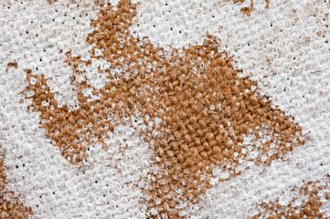 Closeup texture of a roughly painted white and light green canvas lying on a wooden surface. Background for fabric texture. Universal background.