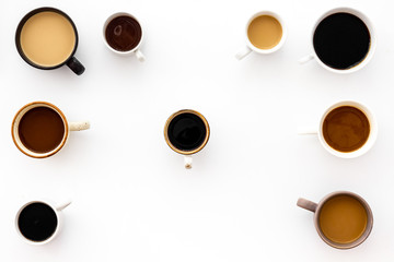 Cups of hot drinks on white desk top view