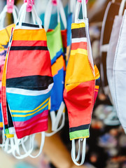 Close up to variety of colorful new face mask handmade sewing from fashion fabric cotton cloth for prevent germs (Covid-19) on sale at street market. Selective focus with blur in the background.
