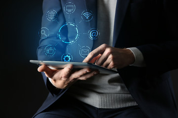 Man with tablet computer on dark background, closeup. Concept of digital marketing