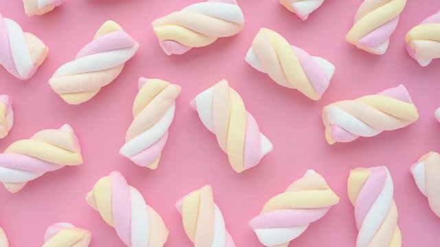 delicious colourful marshmallows pieces lie on pink background and rotate at coffeehouse close upper view